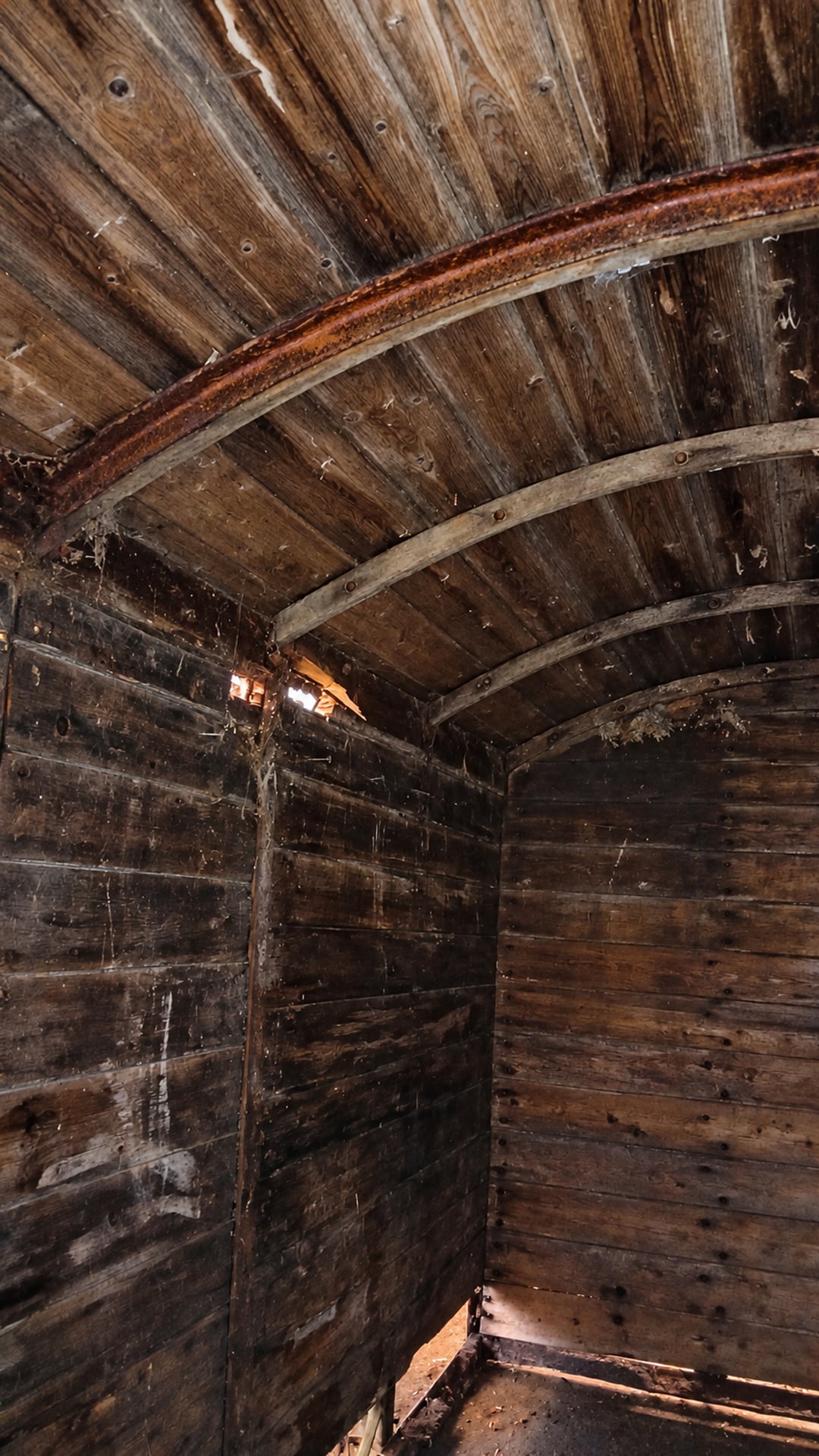 Die gebogenen Dachsparren und das verwitterte Holz im Inneren des Waggons