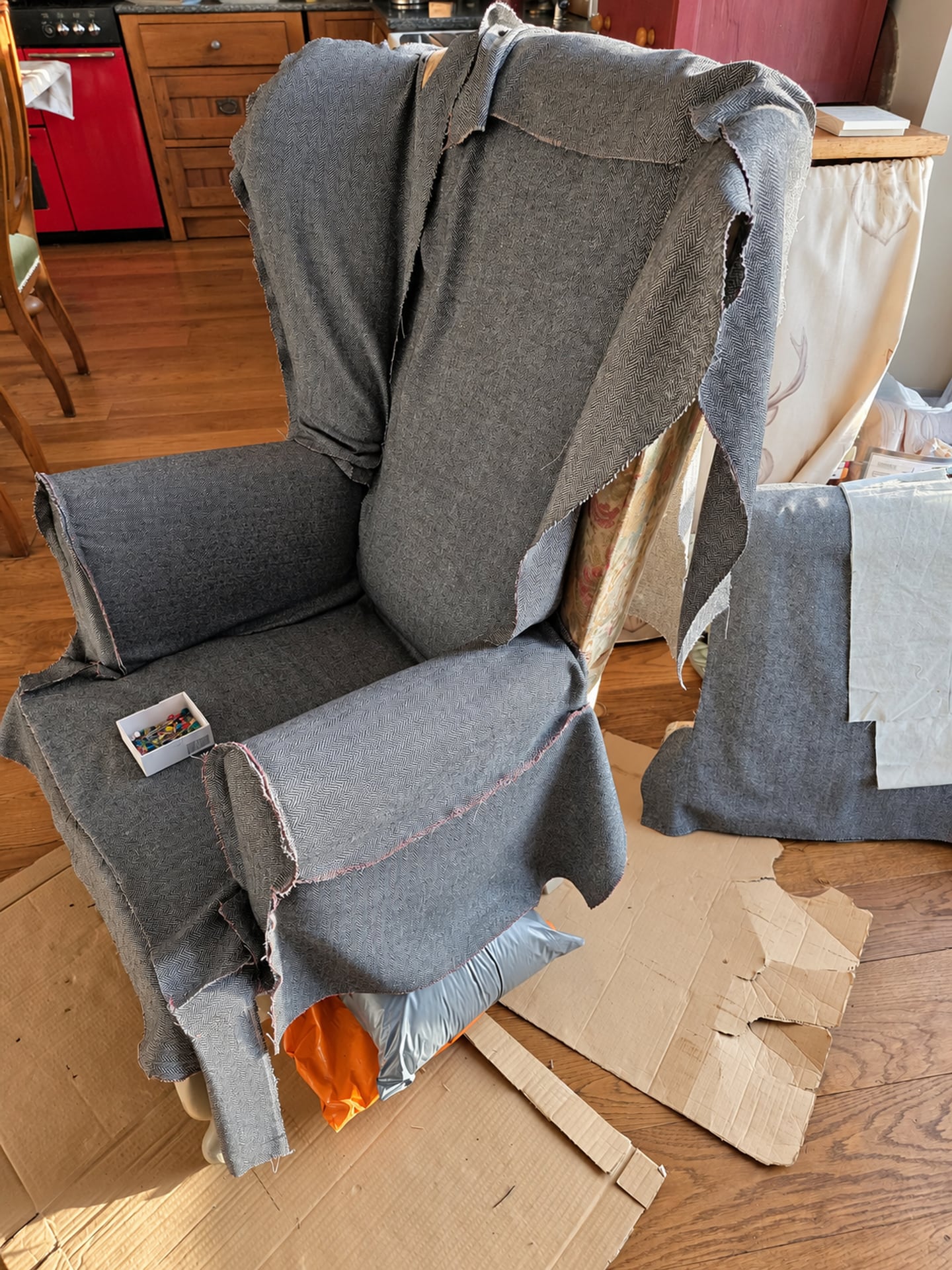 Ein Sessel, der mit grauem Fischgrätenstoff neu bezogen wird