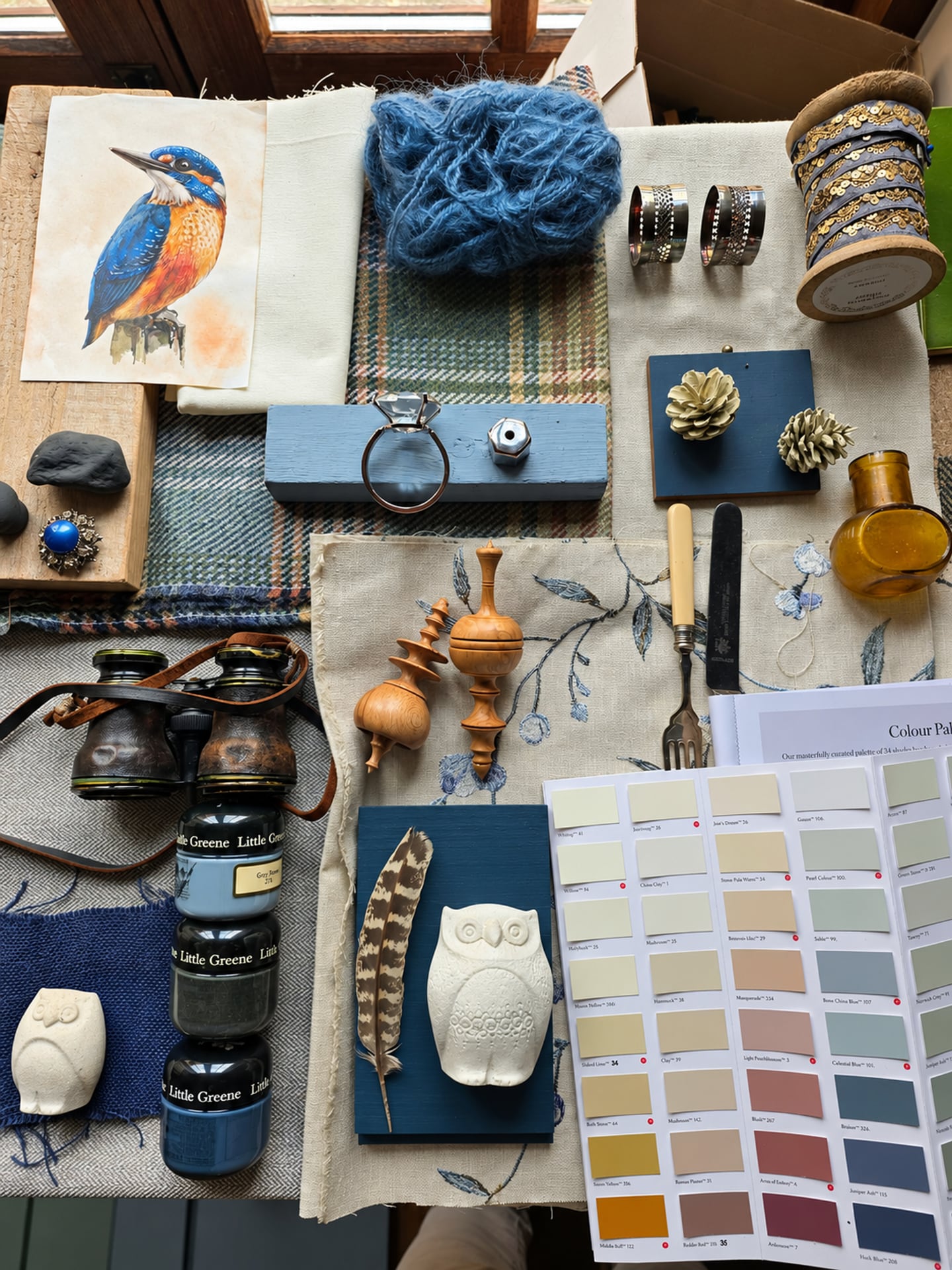 Blaue Stoffe, Vogelkunstwerke, Vintage-Objekte und Farbmuster als Stimmungsbild arrangiert